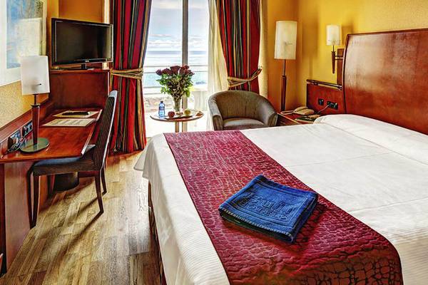Hotelzimmer im Bull Hotel Reina Isabel mit Bett, Schreibtisch, Sessel und Aussicht auf das Meer.