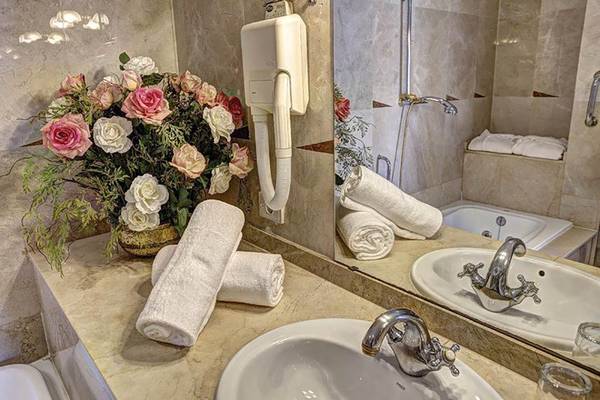 Badezimmer mit Blumenstrauß, Spiegel und Handtüchern im Bull Hotel Reina Isabel & Spa