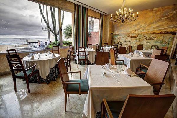 Innenansicht des Restaurants im Bull Hotel Reina Isabel & Spa mit Blick auf das Meer und eine Wandmalerei.