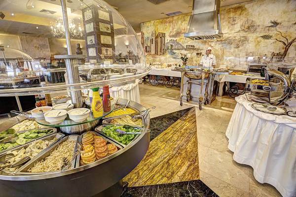 Buffet im Restaurant des Bull Hotel Reina Isabel & Spa mit verschiedenen Speisen und einem Koch, der hinter dem Tresen steht.