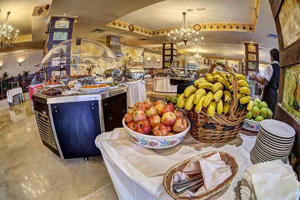 Buffet im Restaurant des Bull Hotel Reina Isabel & Spa mit Obst, Geschirr und Servietten.