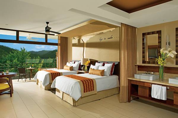 Schlafzimmer im Dreams Las Mareas Costa Rica mit zwei Betten, Balkon, Deckenventilator und Blick auf die Berge.