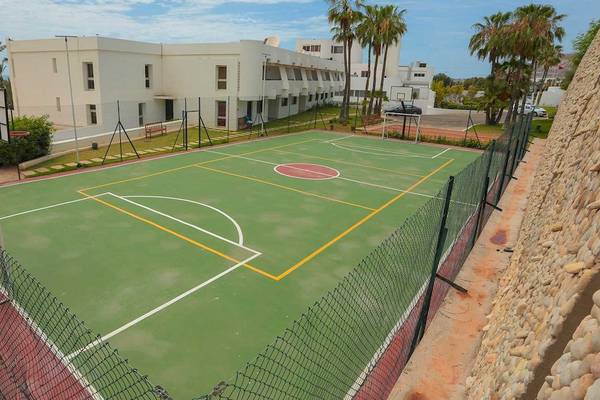 Sportplatz des Allegro Agadir Hotels mit grünem Feld und gelben Linien, umgeben von einer Mauer und Gebäuden.