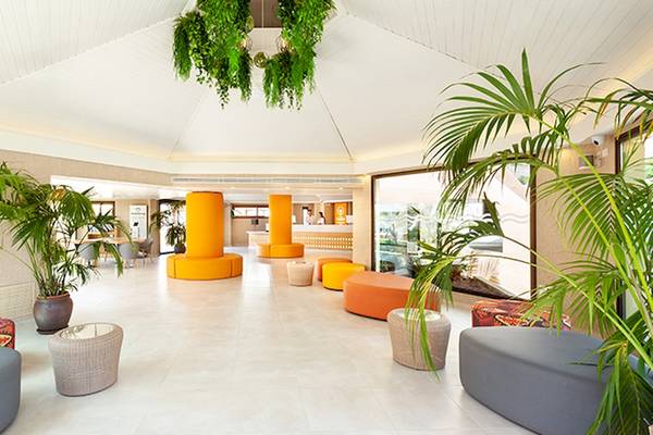 Lobby des Tagoro Family & Fun Costa Adeje Hotels mit modernen Möbeln, Pflanzen und Empfangstresen.