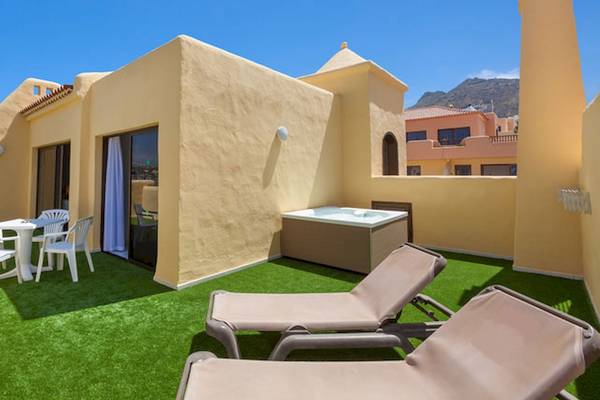 Dachterrasse des Tagoro Family & Fun Costa Adeje mit Whirlpool, Tischen und Stühlen.