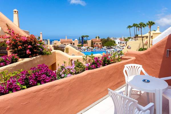 Hotelterrasse mit Blick auf den Pool und Palmen im Hintergrund
