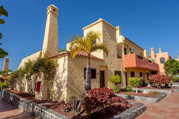 Außenansicht des Tagoro Family & Fun Costa Adeje Hotels mit gelben Gebäuden, gepflasterten Wegen und tropischen Pflanzen.