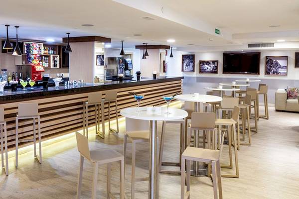 Barbereich im Tagoro Family & Fun Costa Adeje Hotel mit gepolsterten Stühlen und runden Tischen.