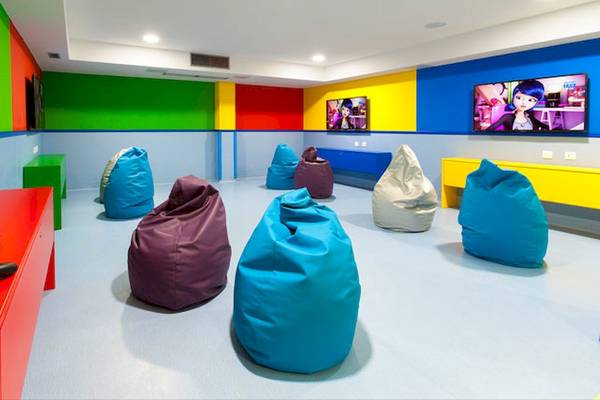 Spielzimmer im Tagoro Family & Fun Costa Adeje mit bunten Wänden, mehreren Fernsehgeräten und bunten Beanbags.