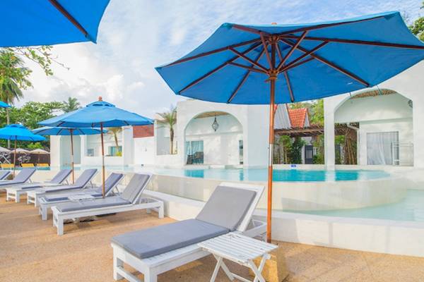 Außenbereich des Ocean Breeze Resort Khao Lak mit Loungestühlen und blauen Sonnenschirmen.