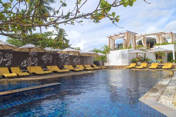 Pool des Ocean Breeze Resort Khao Lak mit gelben Sonnenliegen und Sonnenschirmen.