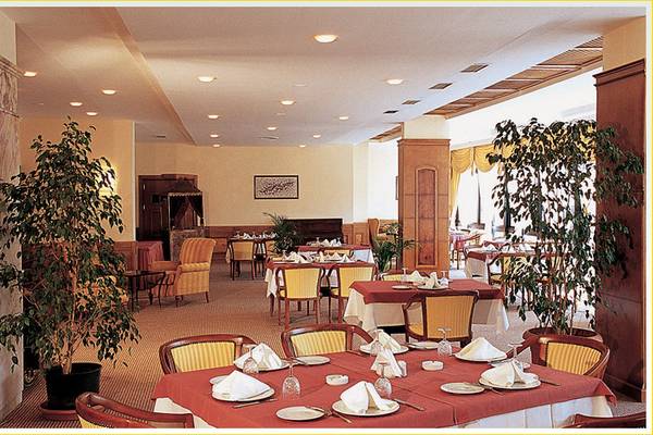 Restaurant im Tusan Beach Resort mit Tischdecken, Stühlen und Pflanzen.