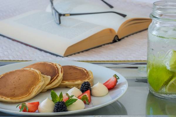 Ein Teller mit Pfannkuchen, Früchten und einem Glas Wasser mit Zitronenscheiben.