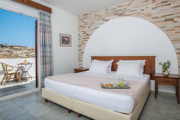 Ein elegantes Zimmer im Naxos Palace Hotel mit einem Bett, Frühstückstablett und Balkonzugang.
