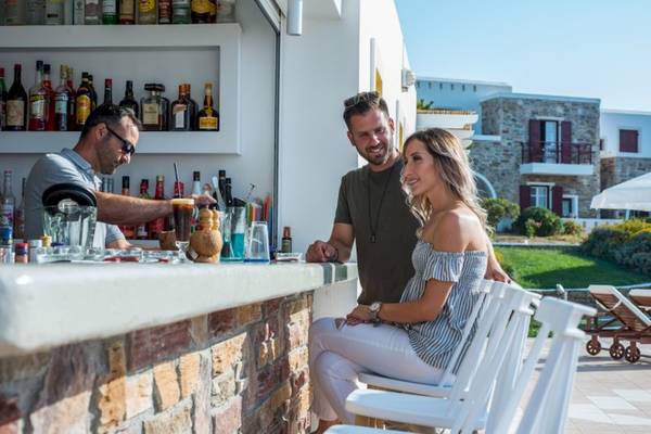 Besucher sitzen an der Bar des Naxos Palace Hotels und genießen Getränke.