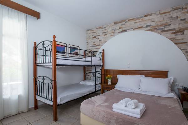 Schlafzimmer mit Doppelstockbett und Bett, beide mit weißen Laken und Kissen.