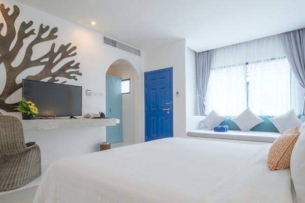 Hotelzimmer im Ocean Breeze Resort Khao Lak mit Fernseher, Bett, Fenster und Meerdekor.