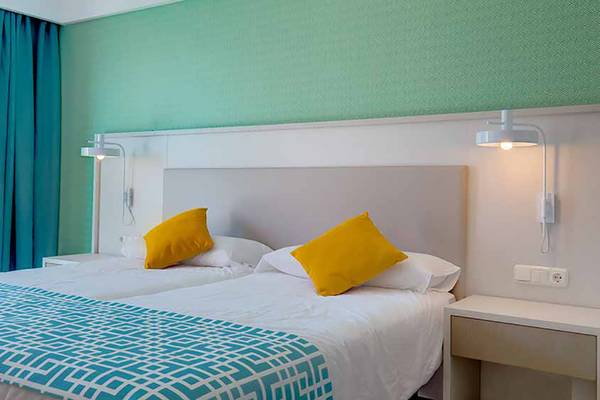 Doppelbett-Zimmer im SBH Maxorata Resort mit blauen und grünen Wänden und gelben Kissen.