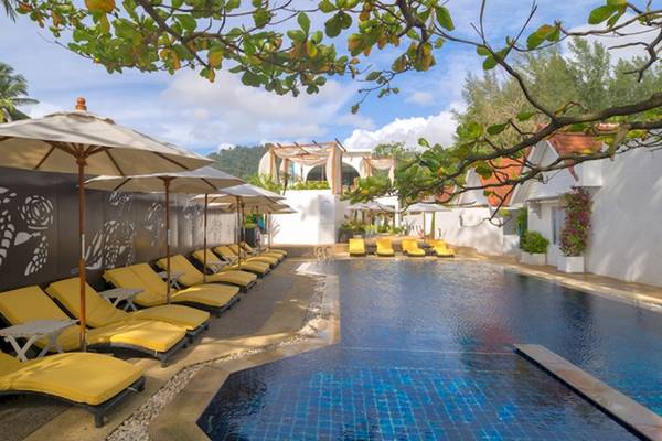 Poolseite des Ocean Breeze Resort Khao Lak mit gelben Liegen und Sonnenschirmen.