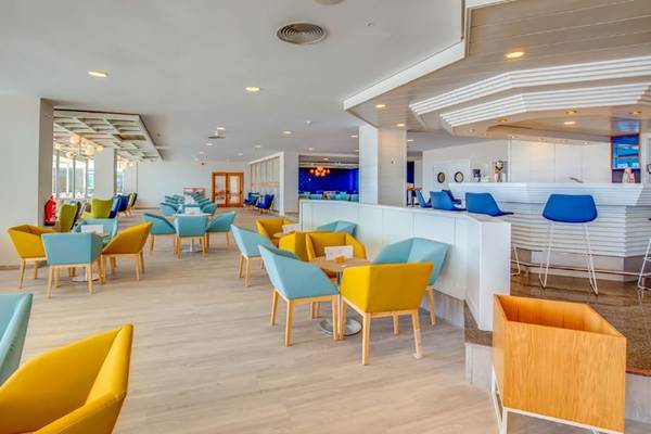 Innenansicht des SBH Maxorata Resorts mit farbenfrohen Stühlen und Tischen, einer Bar und Panoramafenstern.