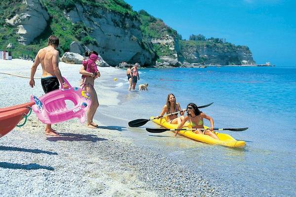 Familie mit Kind am Strand von Aldiana Club Rocca Nettuno Calabria, einige rudern im Kajak.