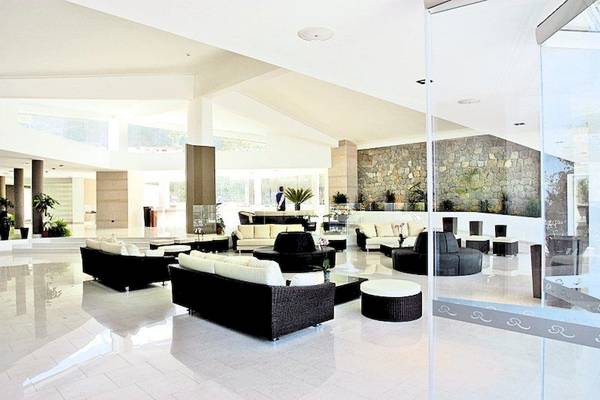 Lobby des Aldiana Club Rocca Nettuno Calabria mit weißen Möbeln und Pflanzen.