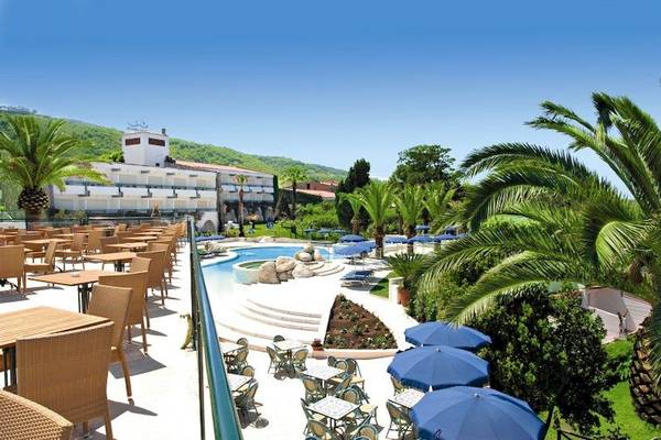 Aussicht auf das Aldiana Club Rocca Nettuno Calabria Hotel mit Pool, Sonnenliegen und Palmen