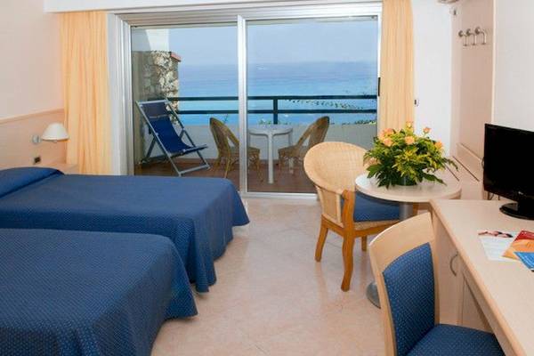 Hotelzimmer mit zwei Betten und Meerblick von der Terrasse.