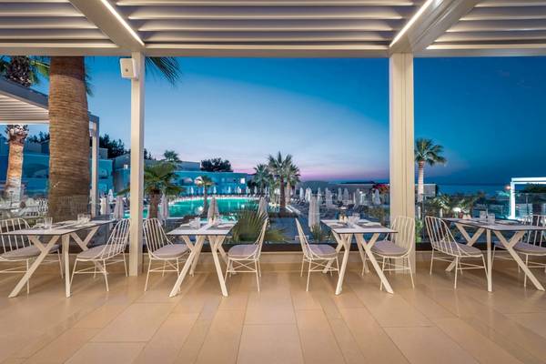 Außenbereich des Mitsis Rodos Village Beach Hotel & Spa mit Tischen und Stühlen.
