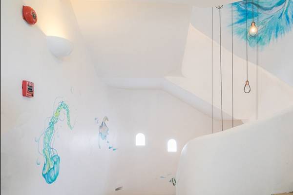 Innenansicht des Ocean Breeze Resort Khao Lak mit einer Wendeltreppe und Wandmalereien.