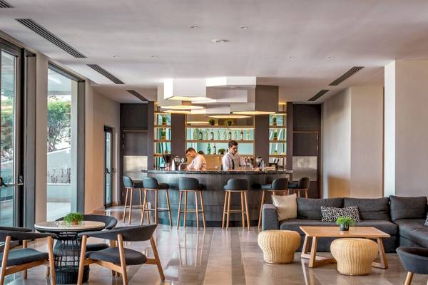 Bar im Mitsis Rodos Village Beach Hotel & Spa mit Barkeepern und Sitzgelegenheiten.