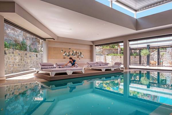 Außenpool des Mitsis Rodos Village Beach Hotel & Spa mit Loungeliegen und einer Frau.