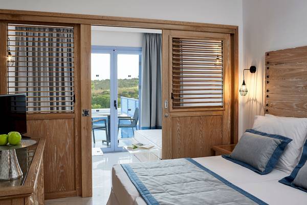 Zimmer im Mitsis Rodos Village Beach Hotel mit Blick auf einen Pool und eine Terrasse.