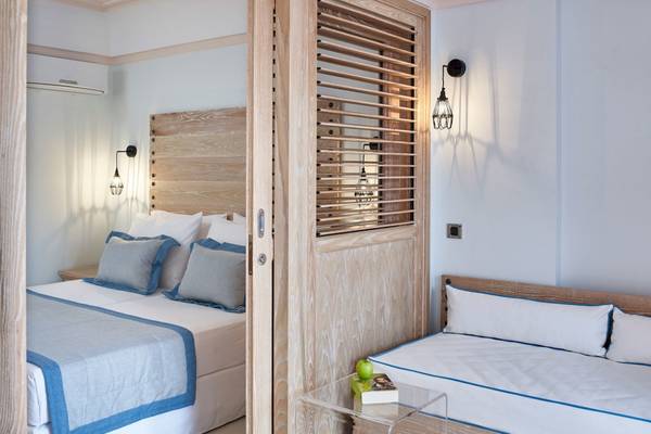 Schlafzimmer im Mitsis Rodos Village Beach Hotel mit zwei Betten, Holzmöbeln und Büchern auf einem Tisch.