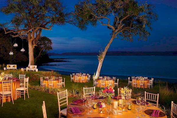 Ein abendessen im freien mit mehreren runden tischen unter freiem himmel am strand des geheimnis papagayo costa rica