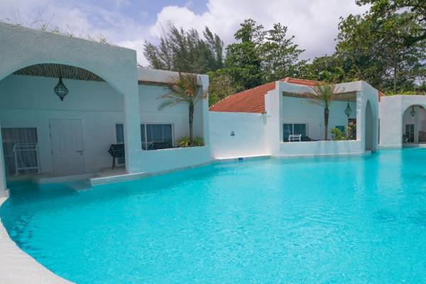 Außenbereich des Ocean Breeze Resort Khao Lak mit einem großen Swimmingpool und weißen Gebäuden.