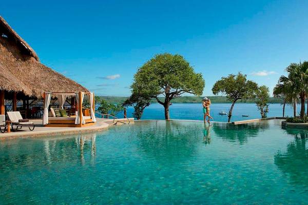 Unendlicher Pool am Secrets Papagayo Costa Rica mit Blick auf das Meer und eine Hütte.