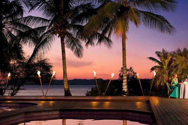 Ein Paar genießt ein Abendessen am Swimmingpool im Secrets Papagayo Hotel bei Sonnenuntergang.