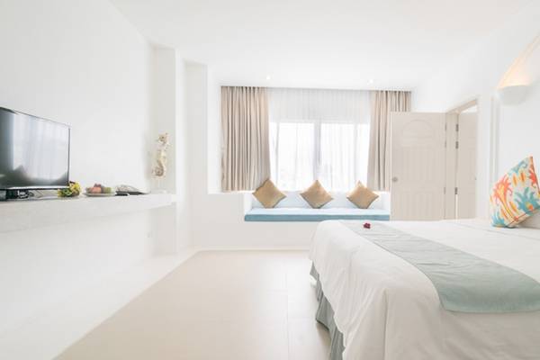 Innenansicht eines Zimmers im Ocean Breeze Resort Khao Lak mit Fernseher und Zitat an der Wand.