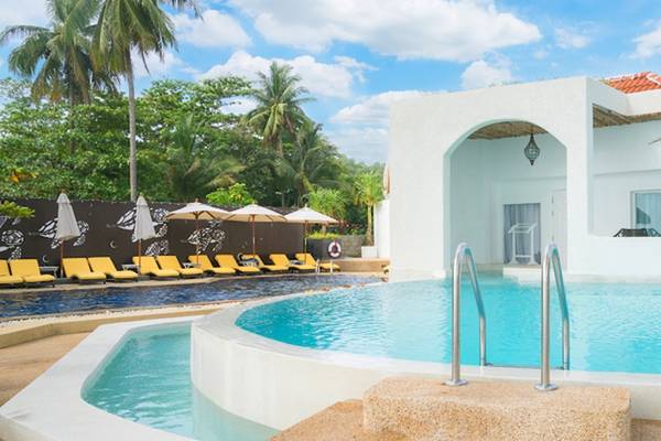 Außenpool des Ocean Breeze Resort Khao Lak mit gelben Sonnenliegen und weißen Sonnenschirmen.