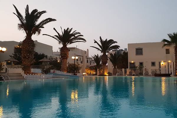 Poolansicht des Europa Beach Hotel & Spa mit Palmen und Gebäuden im Hintergrund.