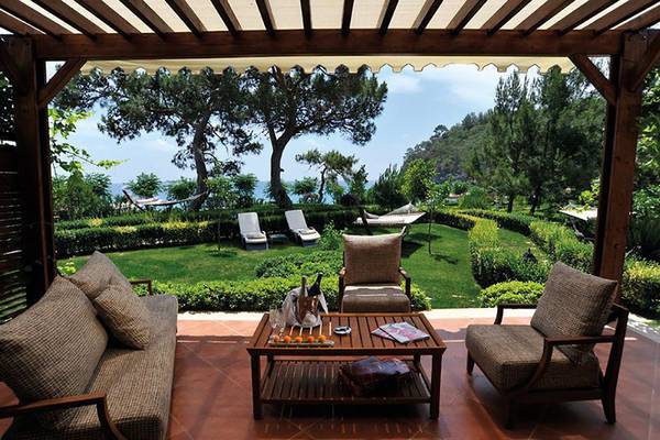 Terrasse mit Sofas und Tisch im Hotel Nirvana Dolce Vita mit Blick auf einen Garten und das Meer.