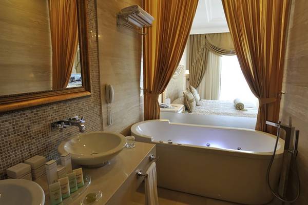 Badezimmer im Nirvana Dolce Vita Hotel mit Badewanne, Waschbecken und Spiegel.