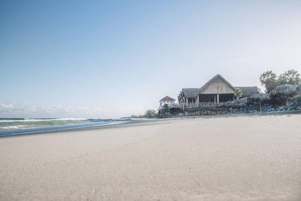 Strand des Iberostar Origin Bella Costa Hotels mit Sonnenliegen und Gebäuden