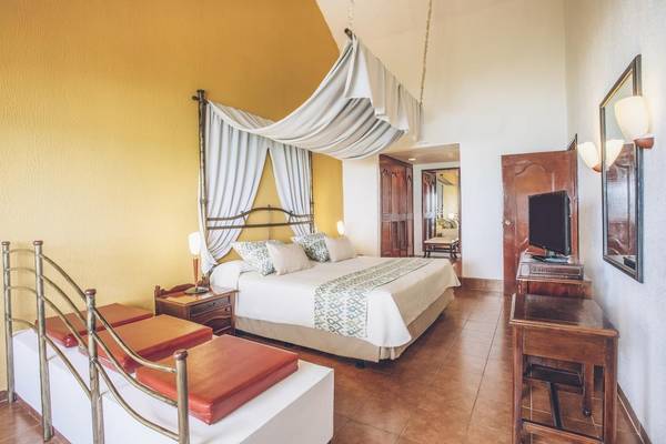 Schlafzimmer im Iberostar Origin Bella Costa Hotel mit einem großen Bett und zwei Nachttischen.