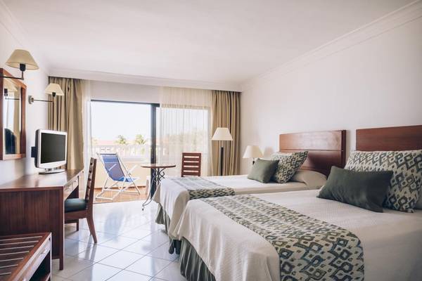 Hotelzimmer mit zwei Betten, Schreibtisch, Fernseher, und Balkon im Iberostar Origin Bella Costa.