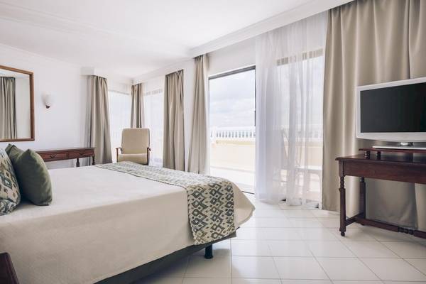 Schlafzimmer im Iberostar Origin Bella Costa Hotel mit Bett, Fernseher, Nachttisch und Balkon