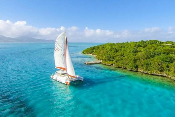 Luftaufnahme eines Katamarans von Preskil Island Resort im türkisfarbenen Wasser vor einer tropischen Küste.