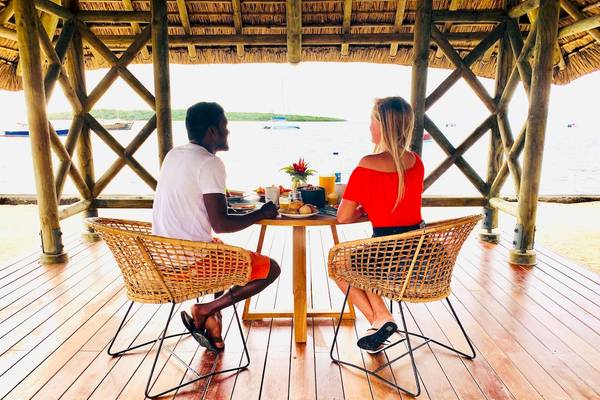 Mann und Frau frühstücken auf einer Holzterrasse im Preskil Island Resort.
