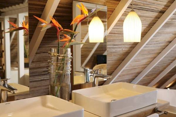 Badezimmer im Preskil Island Resort mit zwei Waschbecken, Blumen in einem Glasvase, und Spiegeln.
